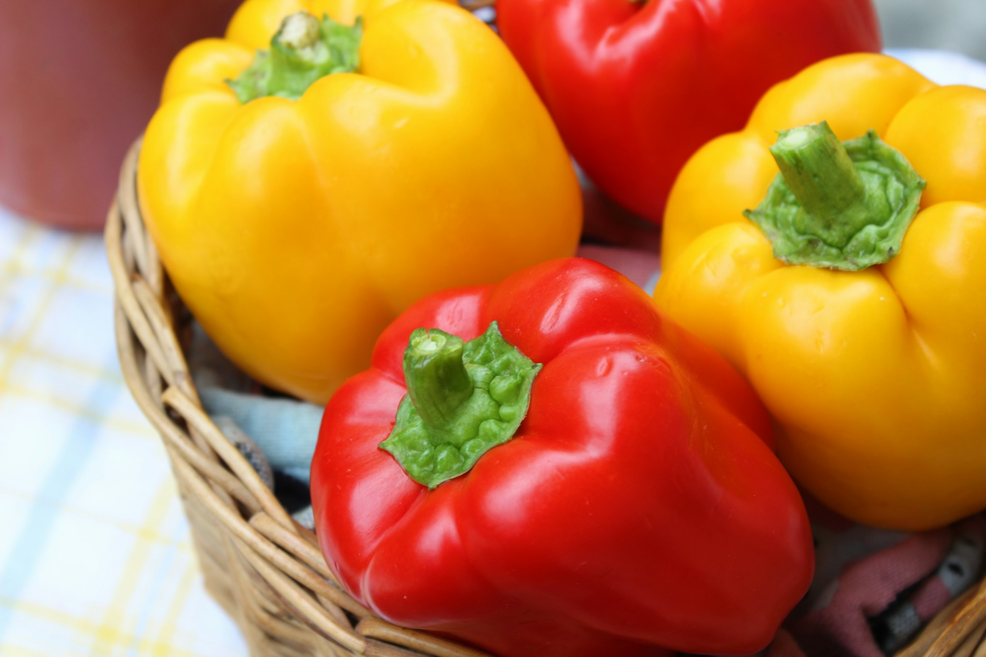 red and yellow bell peppers in brown woven basket